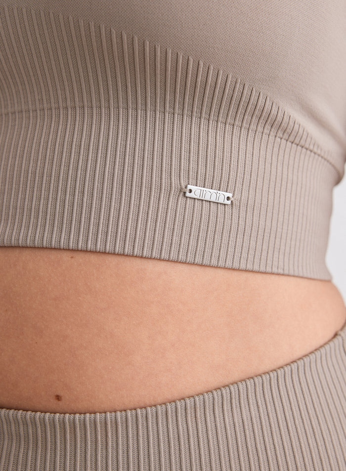 Close-up of the Dark Clay Ribbed Seamless High Support Bra showing the ribbed texture and a silver metal aim'n logo plate.
