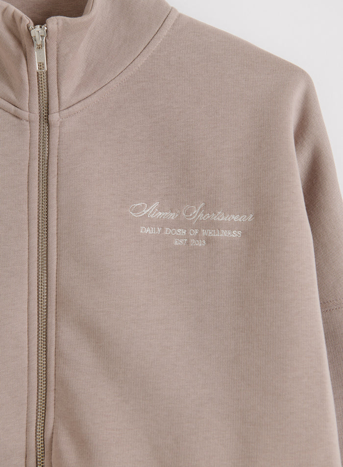 Dark Clay Script Zip Jacket featuring a high collar, silver zipper, and soft aim'n script embroidery.