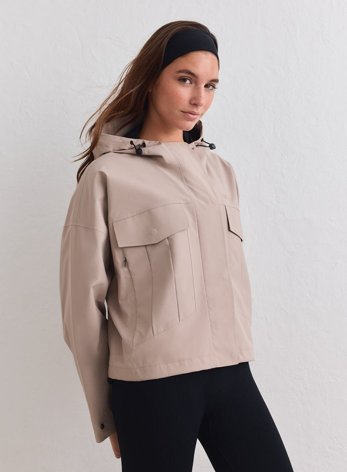 Dark Clay Waterproof Jacket with cargo pockets and a hood, worn by a model for aim'n. [M-178cm]
