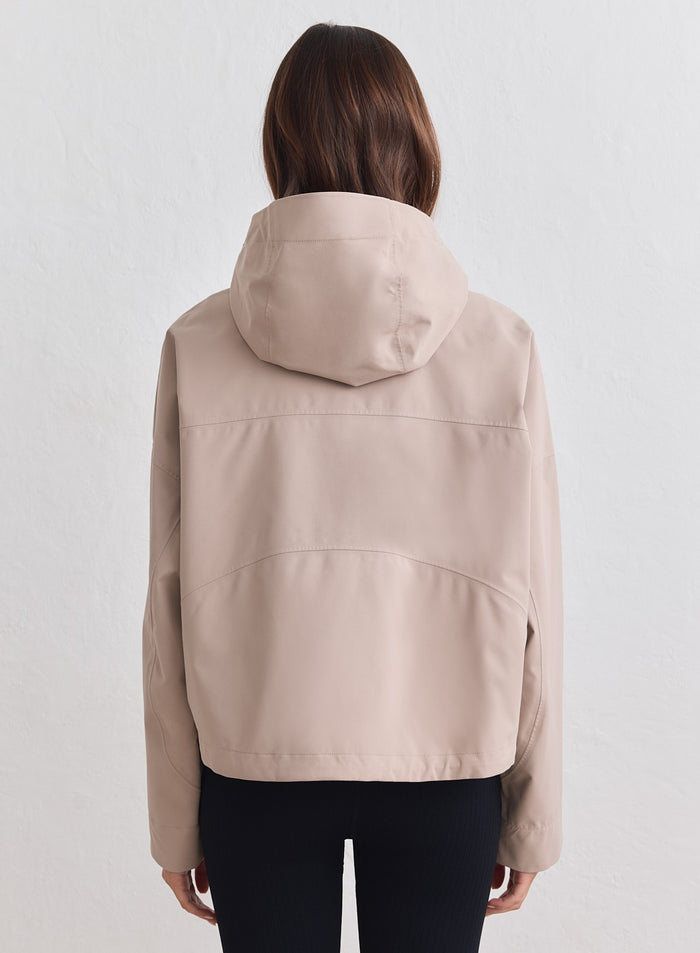 Rear view of a dark clay aim'n waterproof jacket featuring a cropped silhouette and adjustable hood. [M-178cm]