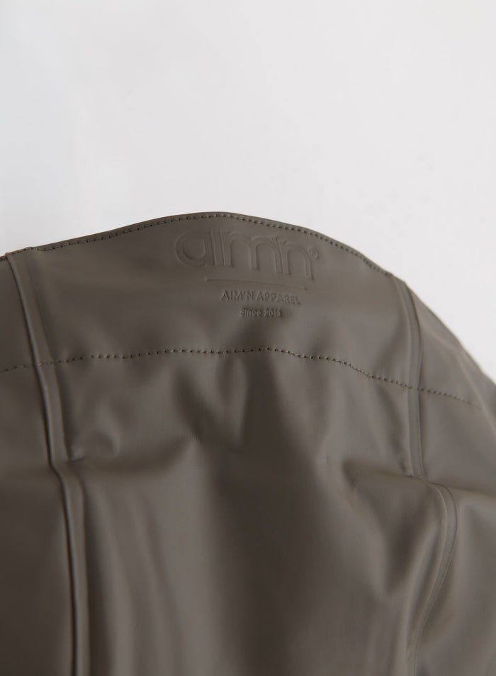 Flatlay detail showing the back yoke and embossed aim'n logo of the Dark Ivy Rain Jacket