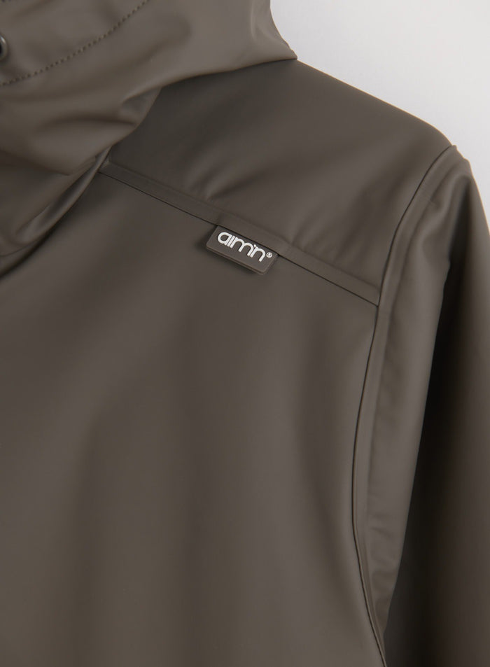 Close-up of the Dark Ivy Rain Jacket showing the back ventilation yoke and aim'n logo branding