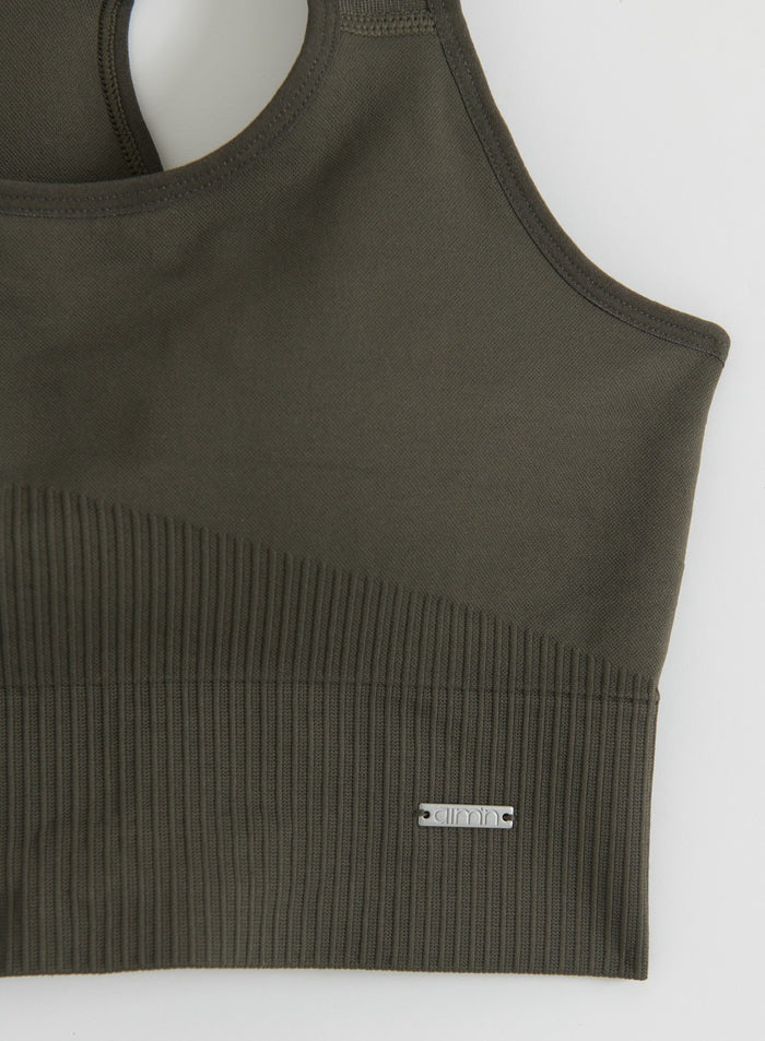 Close-up flat lay of a dark ivy ribbed seamless high-support sports bra with an aim'n logo