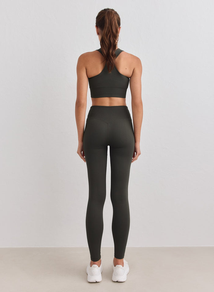 Model wearing dark ivy ribbed seamless petite tights from the back