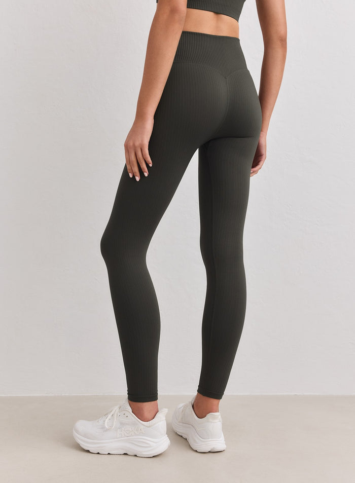 Back view of a model wearing Dark Ivy Ribbed Seamless Tall Tights and white sneakers