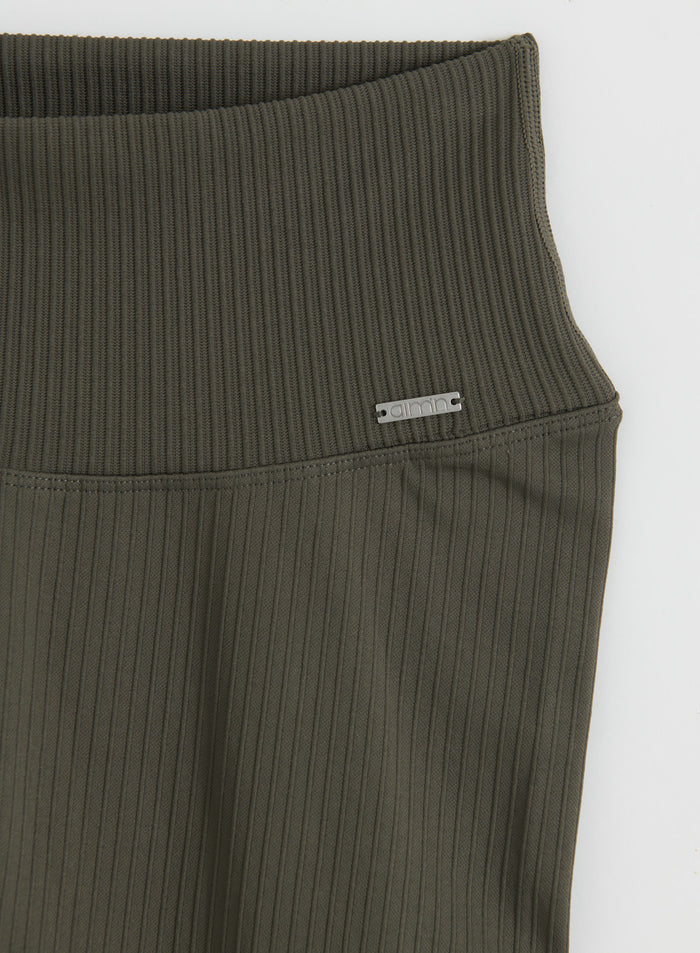 Close-up of the waistband and metal logo badge on Dark Ivy Ribbed Seamless Tall Tights