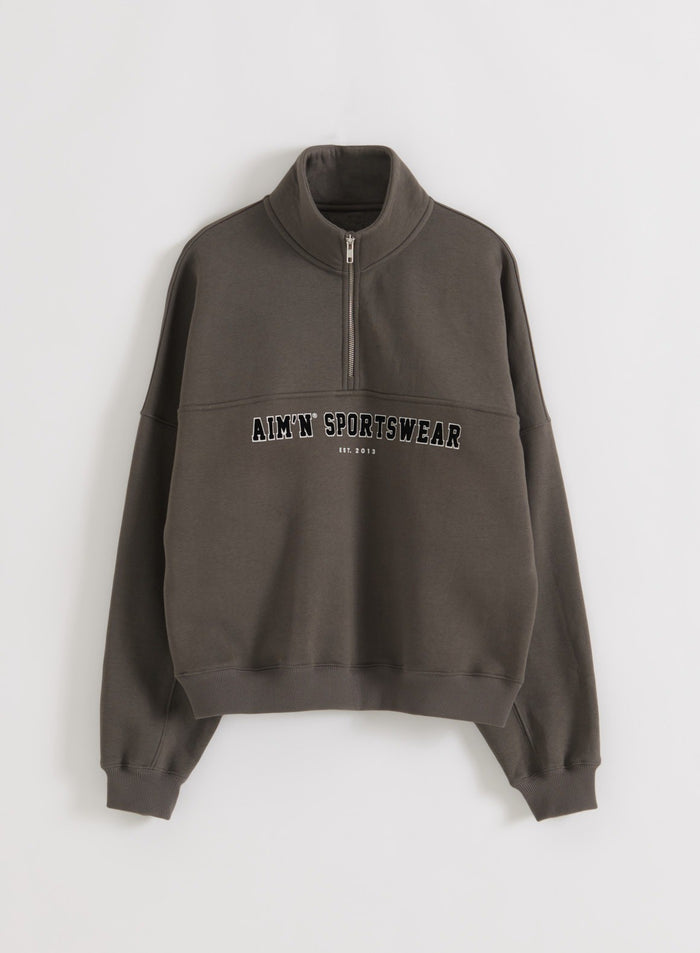 Dark ivy Varsity Sweat Half Zip sweatshirt flat lay with stand collar, front half zip, ribbed cuffs and hem, and varsity-style chest graphic
