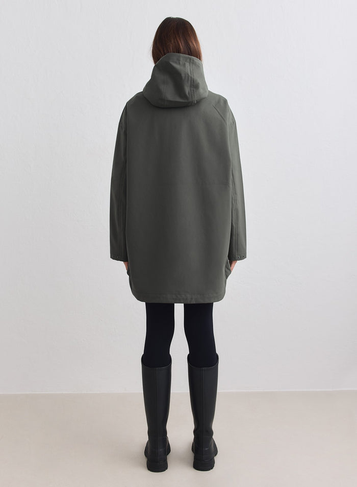 Dark Ivy Waterproof Oversized Anorak by aim'n shown from behind with a protective hood. [M-178cm]
