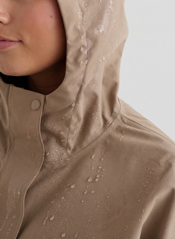 Close-up of a person wearing the Espresso Waterproof Oversized Anorak with water droplets on the hood and fabric