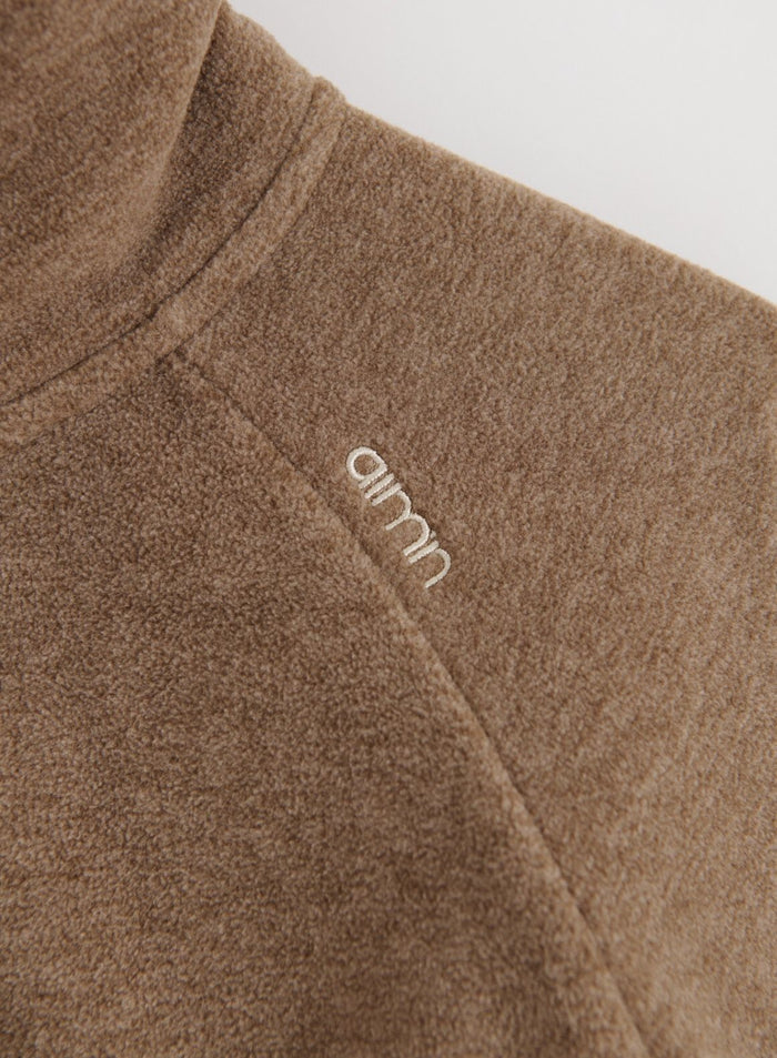 Close-up of the Hazelnut Fleece Zip Jacket showing the embroidered aim'n logo on the shoulder