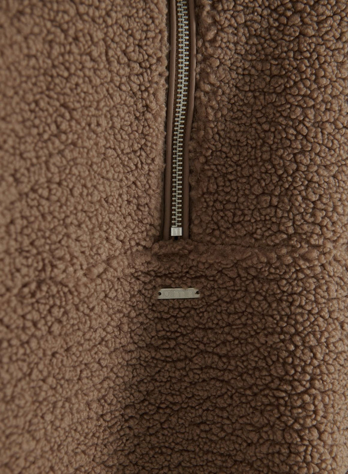 Close-up of hazelnut pile half-zip fleece showing the zipper and aim'n metal logo tag