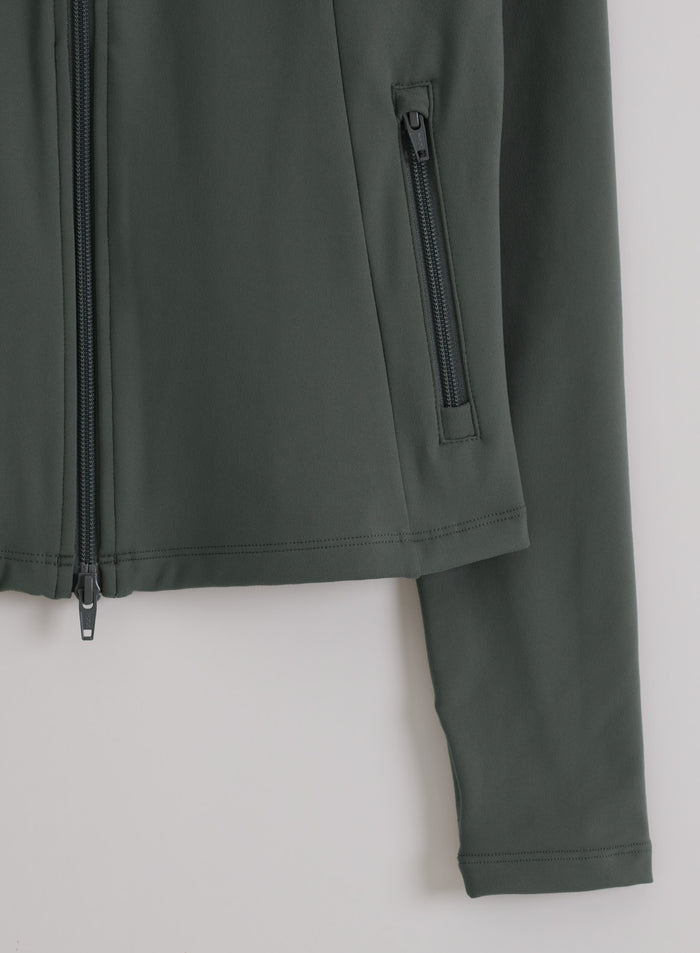 Close-up of the ivy green Sense Zip Jacket by aim'n, featuring a two-way zipper and functional zipped side pocket.