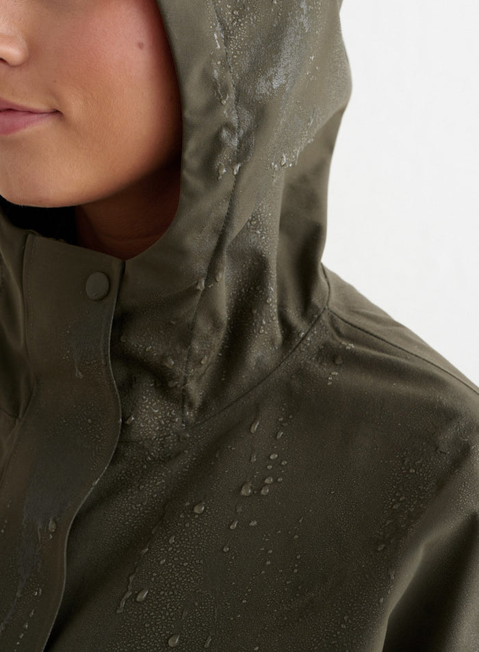 Close-up of the Khaki Waterproof Oversized Anorak by aim'n, showing water droplets on the hood and fabric to highlight its waterproof quality.