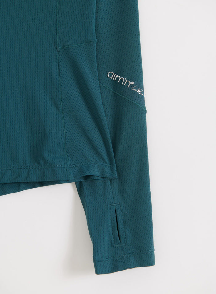 Close-up of the sleeve detail showing the subtle aim'n logo on the lagoon running zip long sleeve