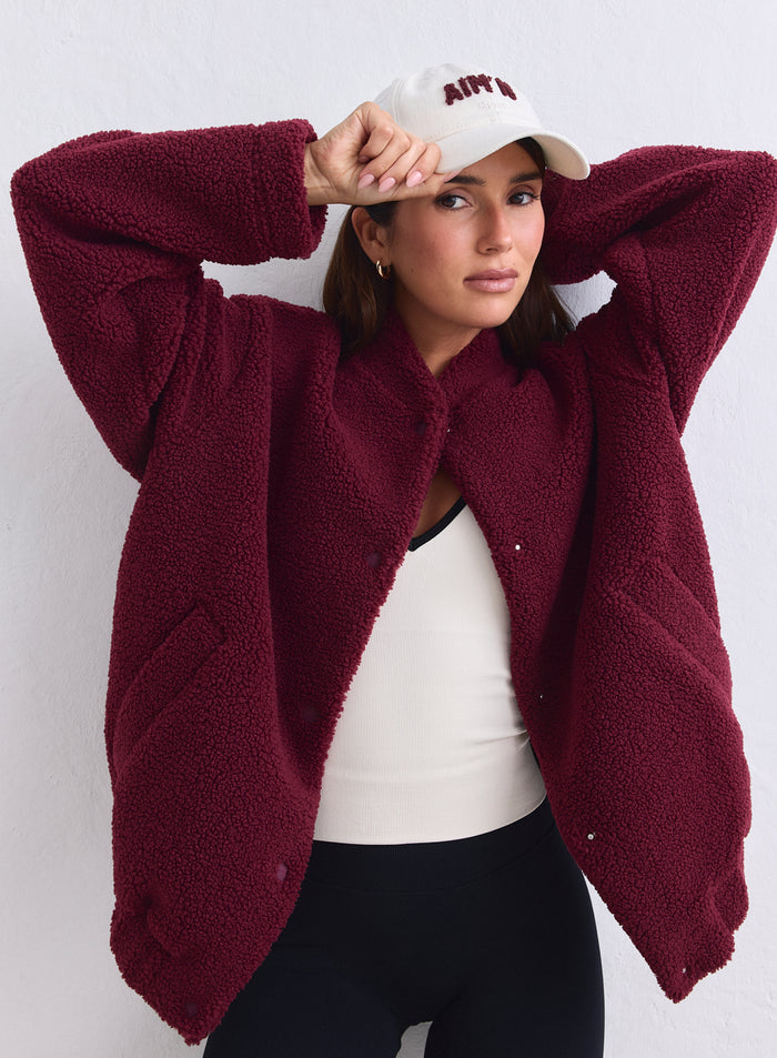 Merlot pile coach jacket in a soft teddy material worn with an aim'n cap by a model. [S-165cm]