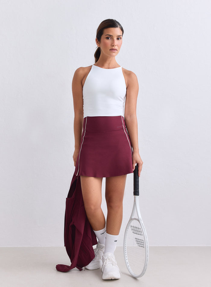 Merlot Sense Contrast Skort with white piping from aim'n, styled with a tennis racket. [XS-165cm]