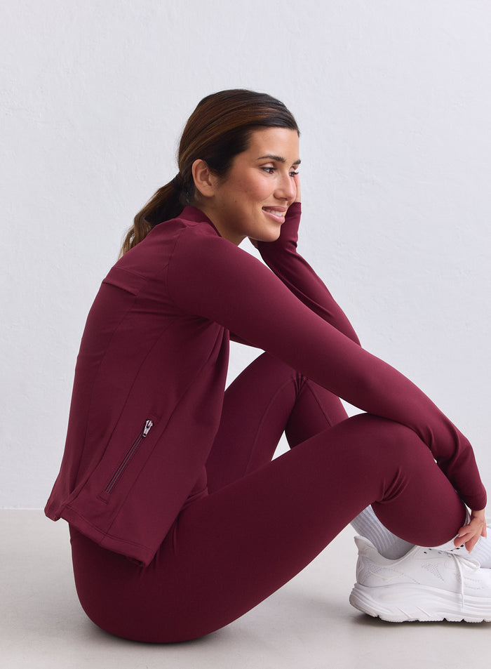 Merlot aim'n Sense Zip Jacket with a second skin feel, shown from the side on a sitting model. [XS-165cm]