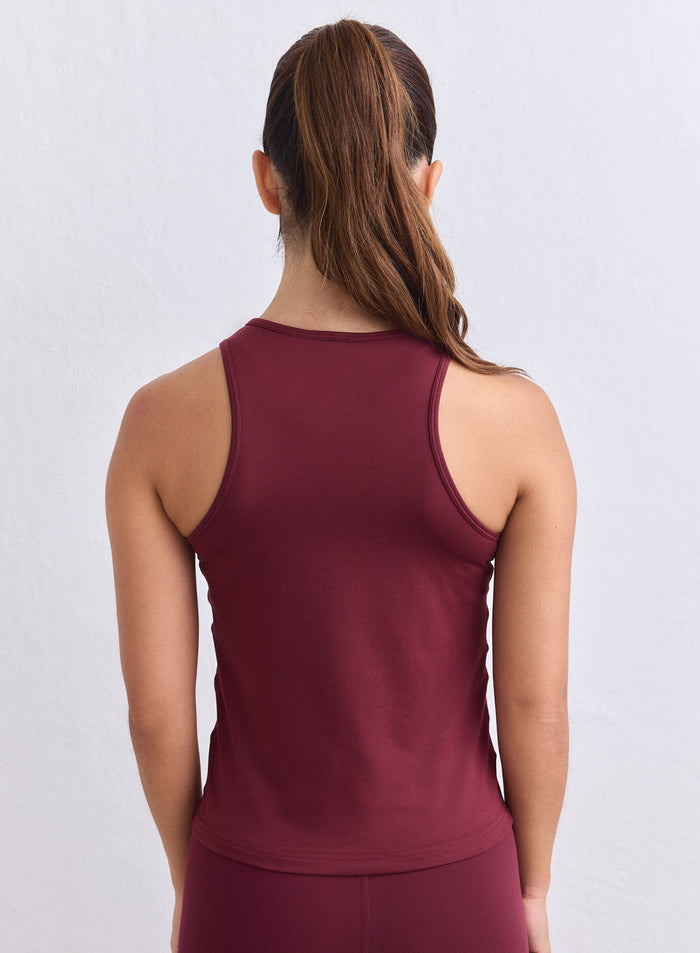 Back view of a woman wearing a merlot aim'n Soft Basic Singlet with her hair in a ponytail. [s-165cm]