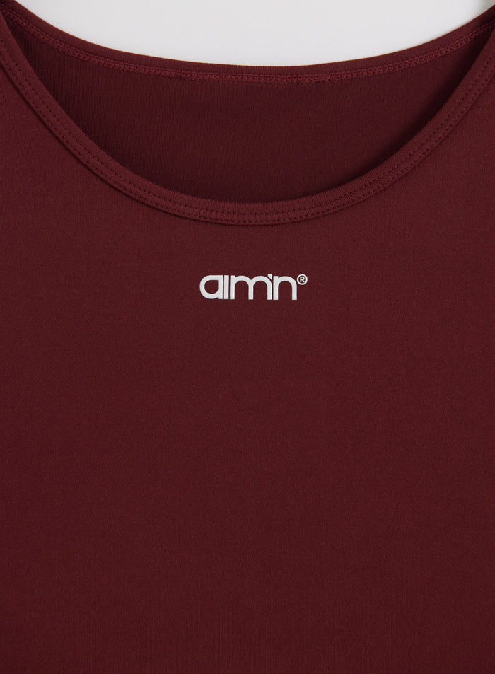 Merlot Soft Basic Singlet close-up showing the round neckline and white aim'n logo on moisture-wicking fabric.