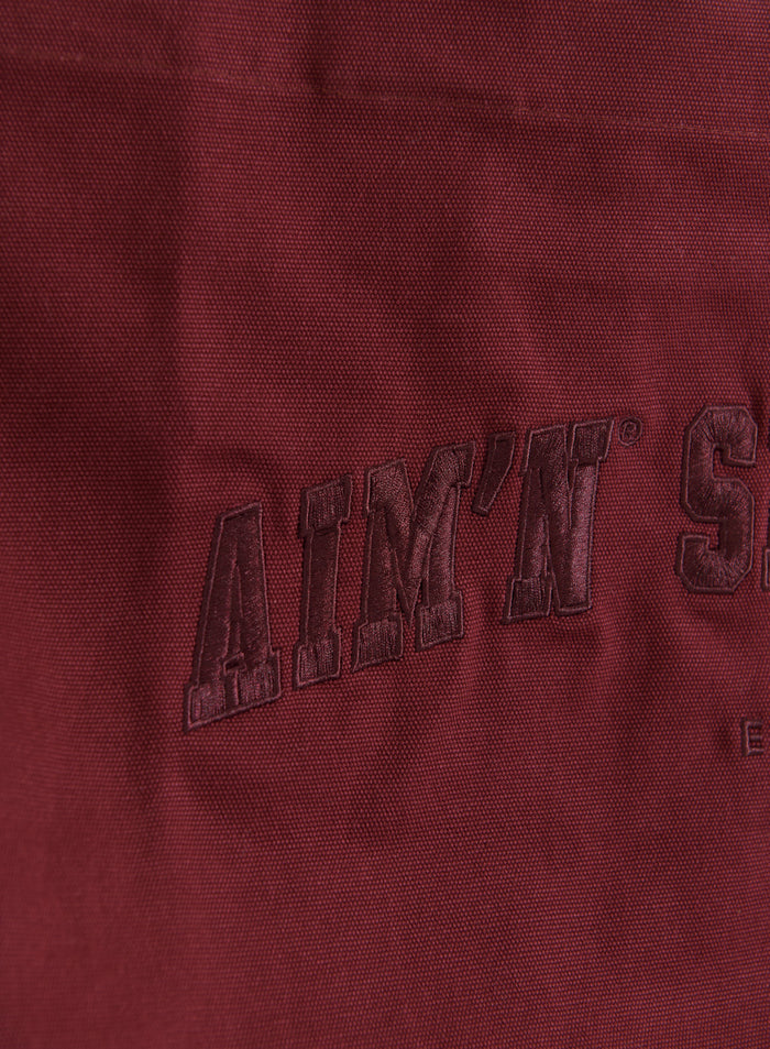 Merlot cotton canvas varsity tote bag featuring tonal embroidered aim'n logo in a classic collegiate-style font.