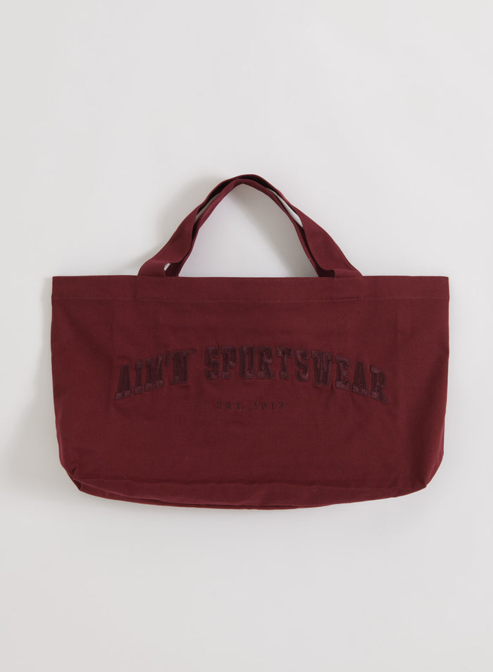 Merlot cotton Varsity Tote Bag with tonal aim'n sportswear logo, displayed in a flatlay.