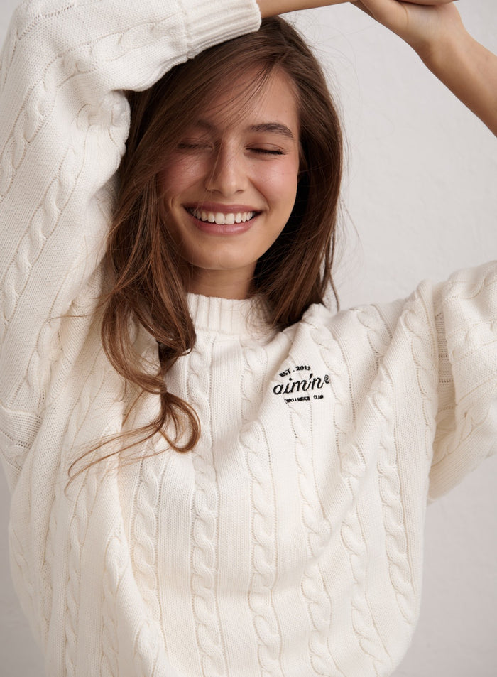 Off-white aim'n Club Cable Knit Sweater with a chest logo detail worn by a smiling woman. [M-174cm]