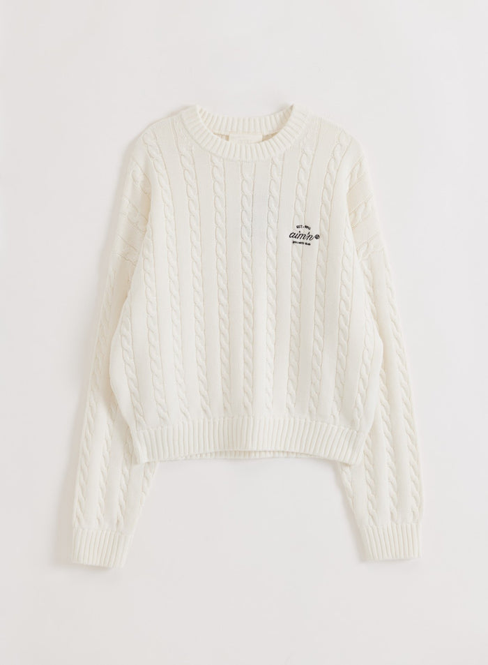 Off-white cotton cable knit sweater from aim'n with a crew neck and logo detail in a flat lay style.
