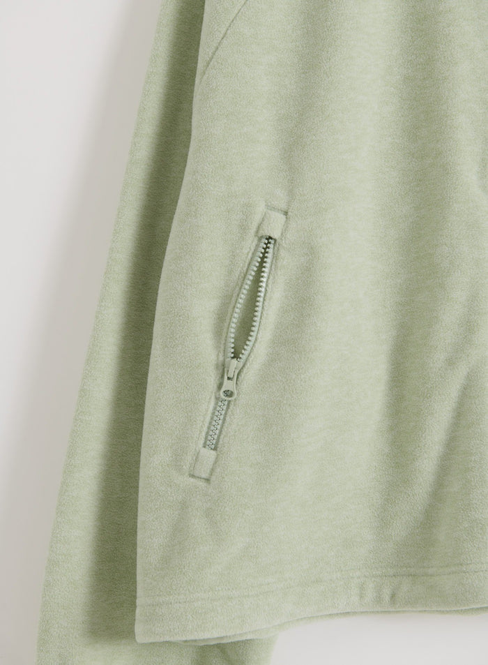 Close-up detail of the zippered pocket on the pistachio fleece zip jacket