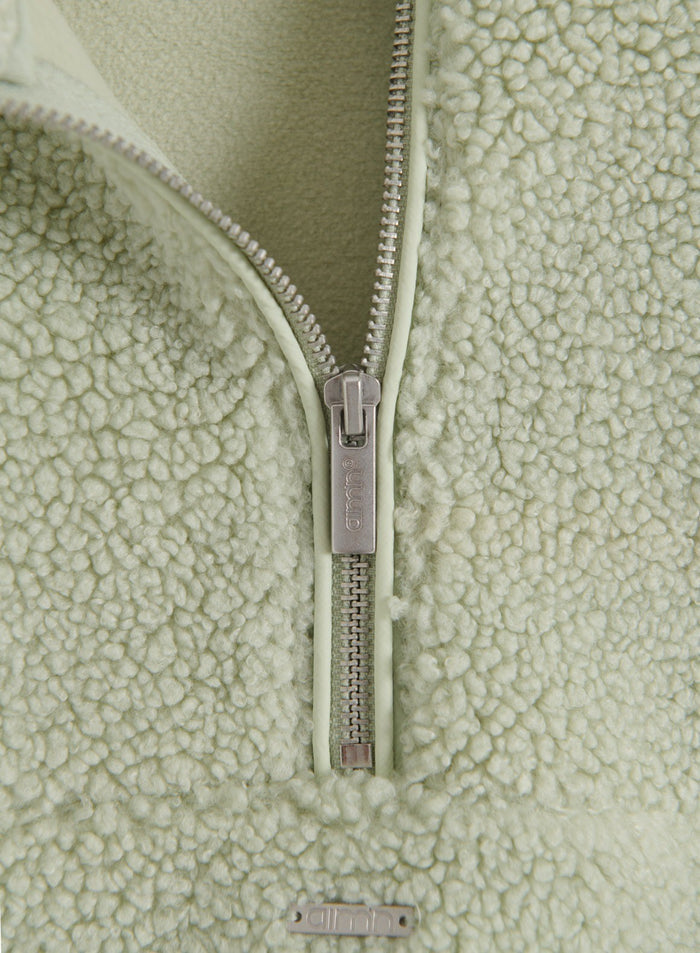 Close-up detail of the zipper and fuzzy pile fleece texture on the Pistachio Pile Half Zip jacket