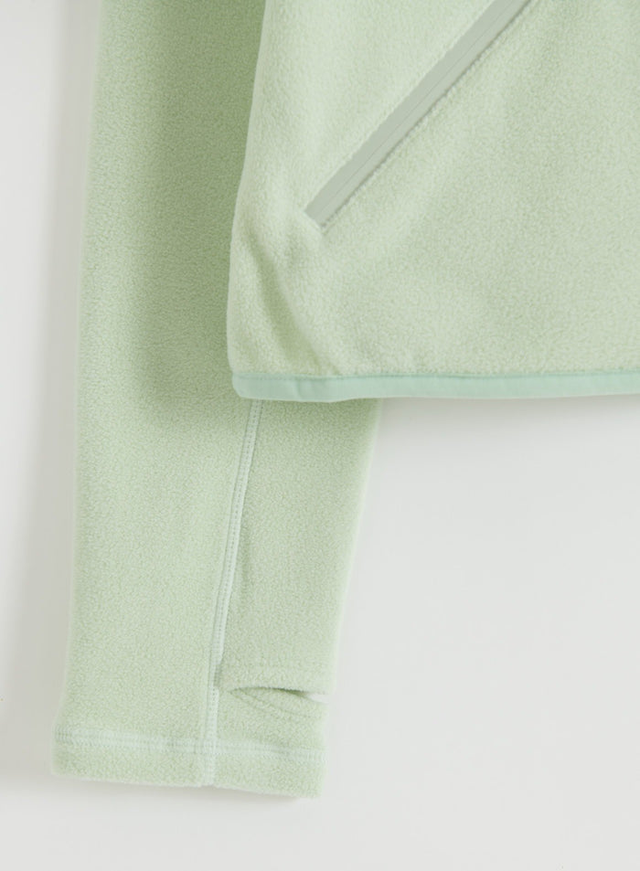 Close-up of the sleeve and pocket detail on the pistachio stretch fleece zip jacket