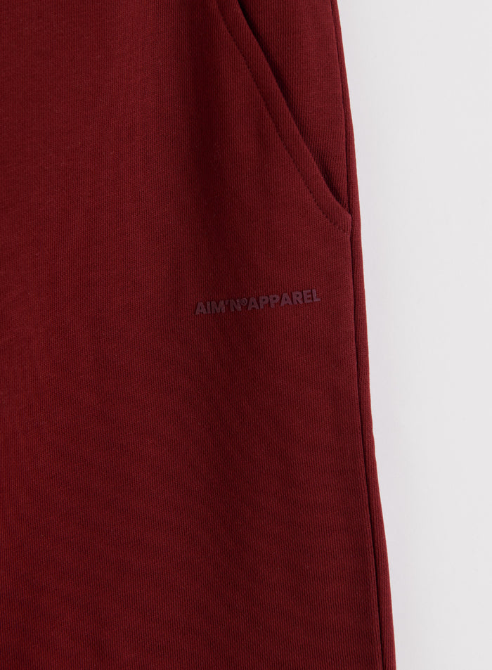 Close-up of ruby red Chunky Terry Sweatpants featuring a side pocket and subtle tonal aim'n logo.