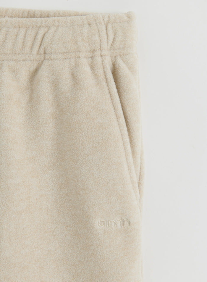 Close-up of the sand fleece pants featuring a pocket and the aim'n logo
