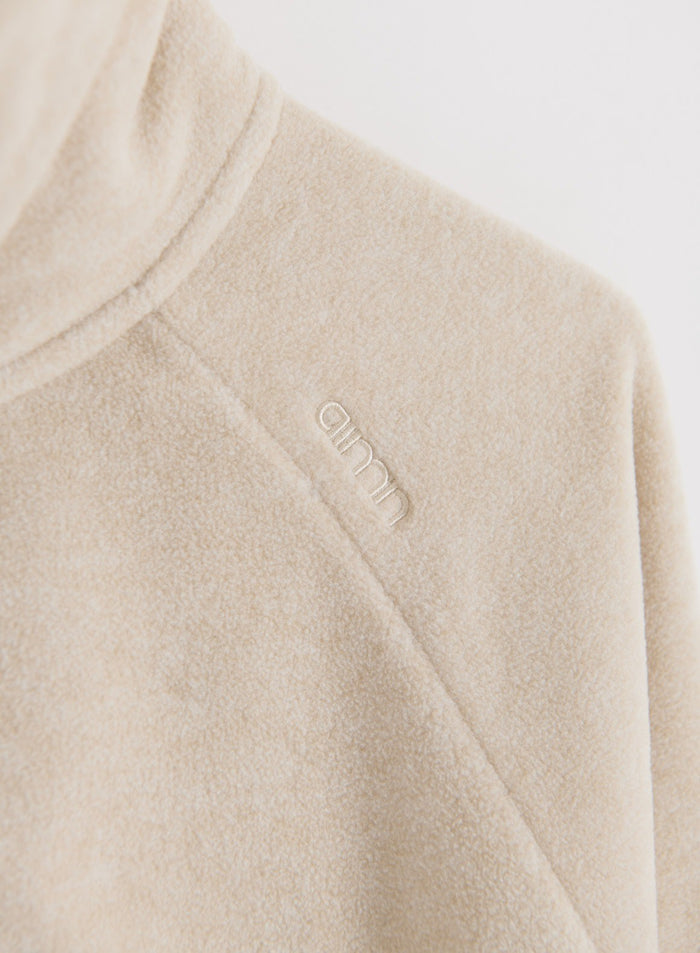 Close-up of sand fleece jacket fabric with embroidered aim'n logo