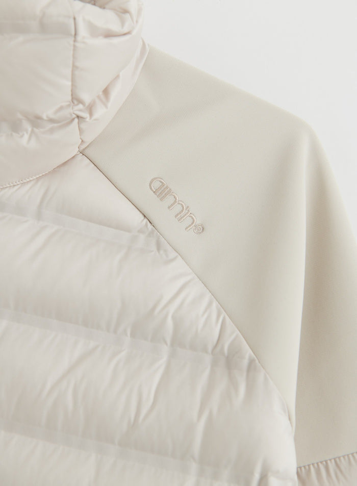 Close-up of the sand Hybrid Jacket showing a quilted insulated panel, stretch sleeve and aim'n logo
