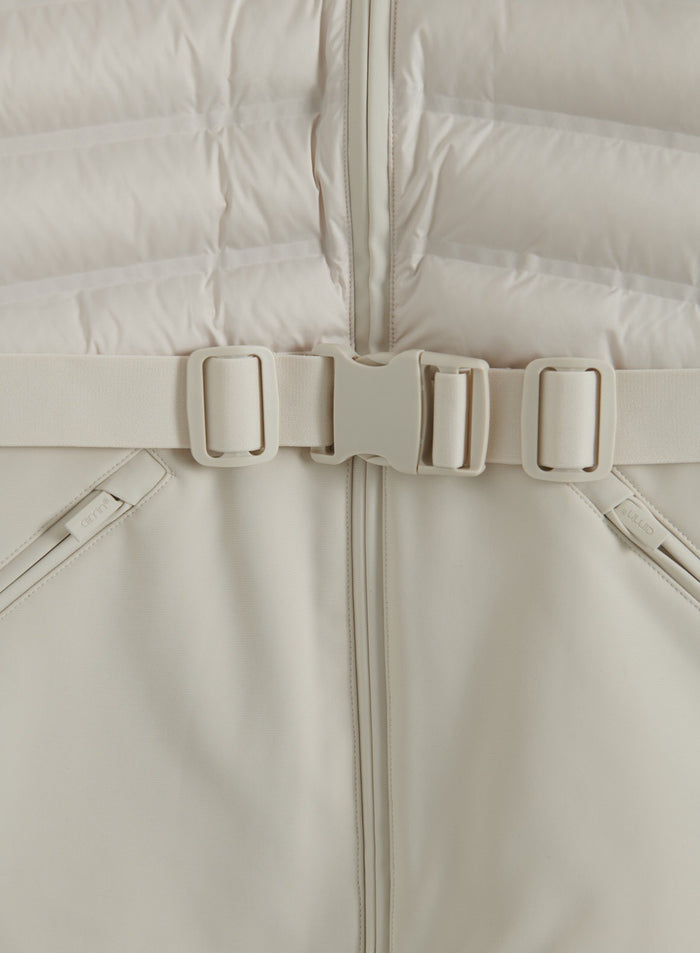 Close-up of a sand hybrid jacket showing padded panels, a front zip and an adjustable buckle detail