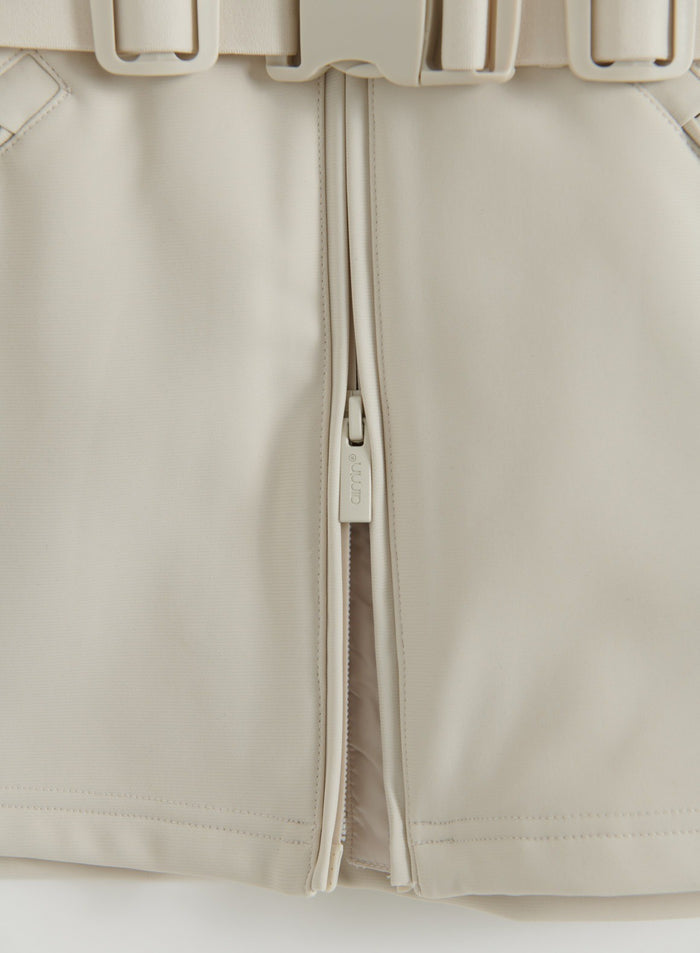 Close-up flatlay of a sand Hybrid Jacket showing the front zipper, zipper pull and stitched panels
