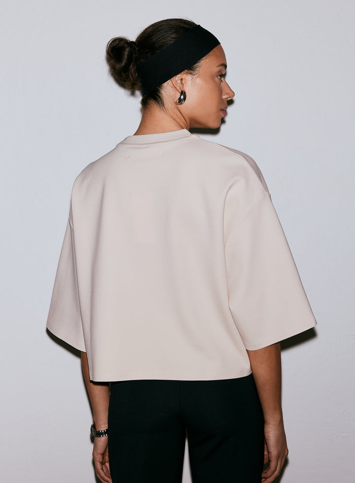 Back view of a model wearing the sand Luxe Boxy Short Sleeve t-shirt and a black headband [M-170cm]