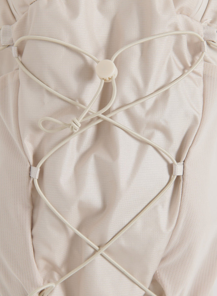 Close-up of a sand outdoor daypack with elastic cord detailing and a central toggle