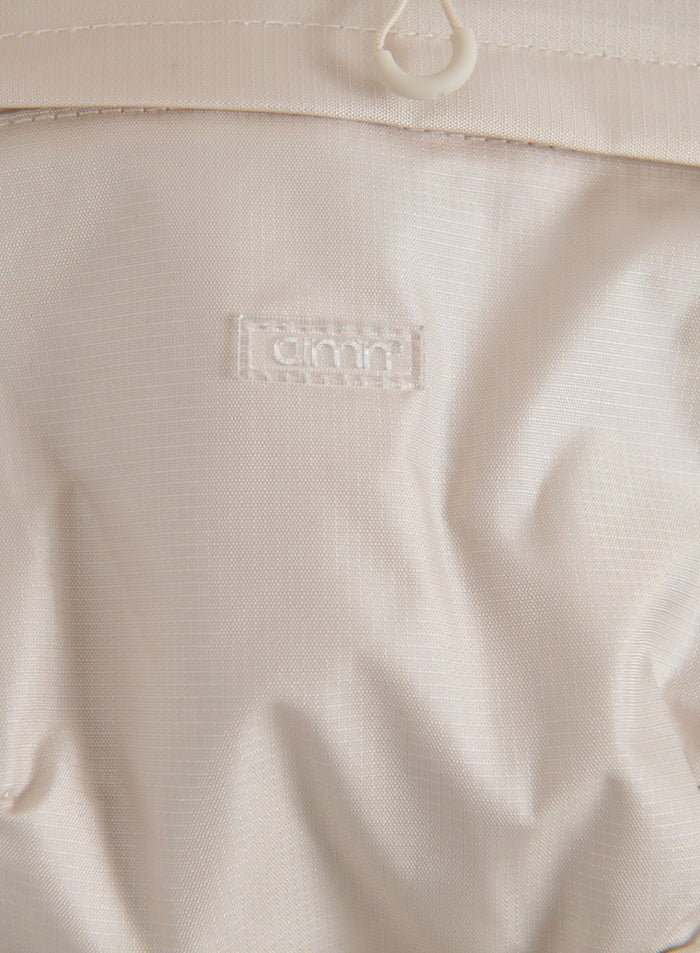 Close-up of the sand aim'n Outdoor Daypack fabric, drawstring detail and logo
