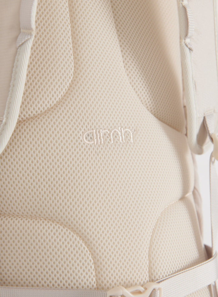 Close-up of the sand Outdoor Daypack showing the breathable mesh back panel, straps, buckle and aim'n logo