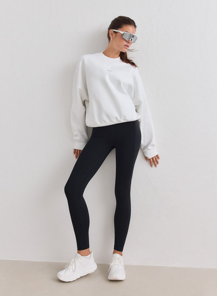 White relaxed-fit aim'n running sweatshirt paired with black leggings and white sneakers [M-178cm]