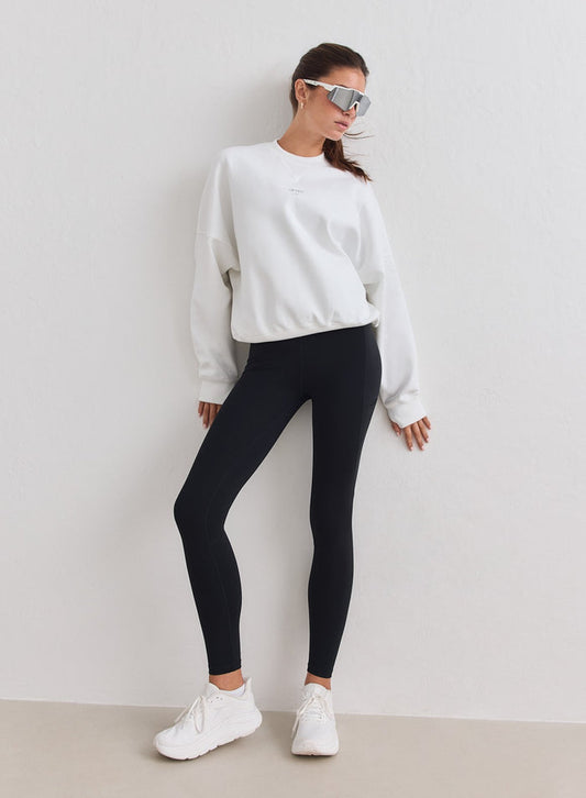 White relaxed-fit aim'n running sweatshirt paired with black leggings and white sneakers [M-178cm]