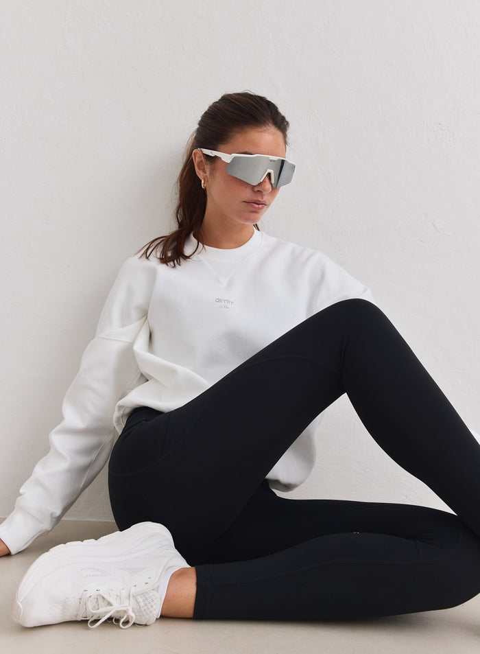 White relaxed-fit running sweatshirt by aim'n worn with black leggings and sporty sunglasses. [M-178cm]