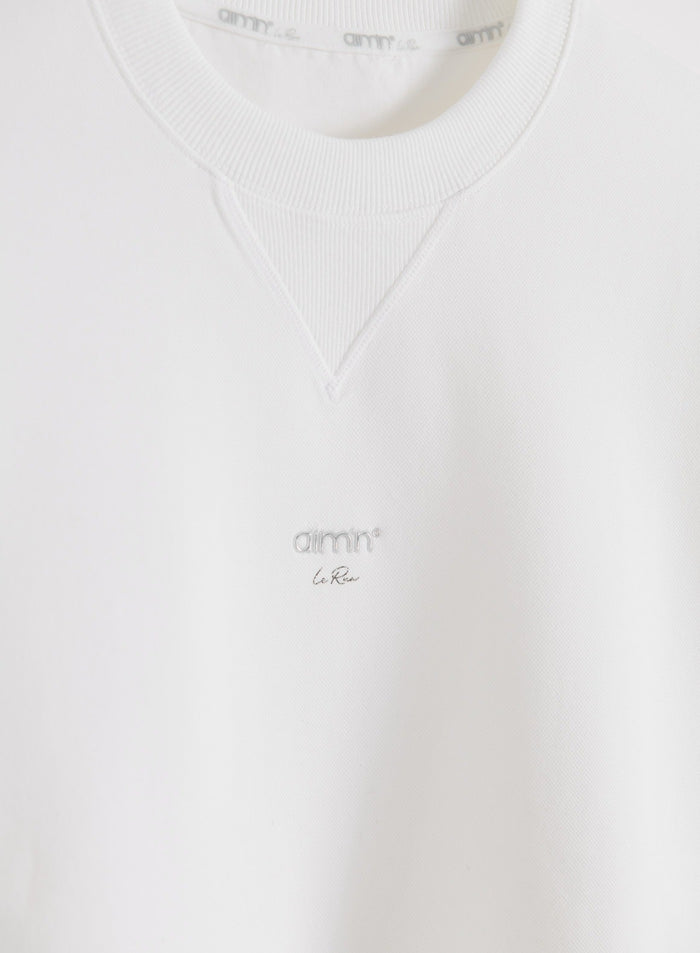 White aim'n Le Run Running Sweatshirt close-up showing chest logo and collar