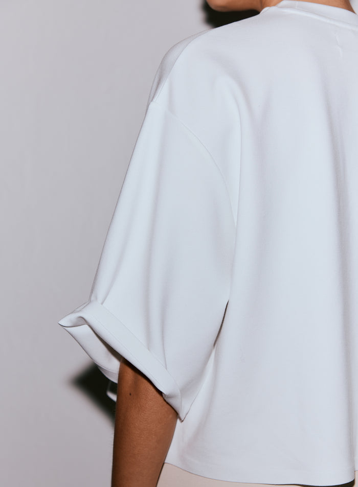 Close-up of the back and cuffed sleeve of a white Luxe Boxy Short Sleeve top worn by a person. [M-170cm]