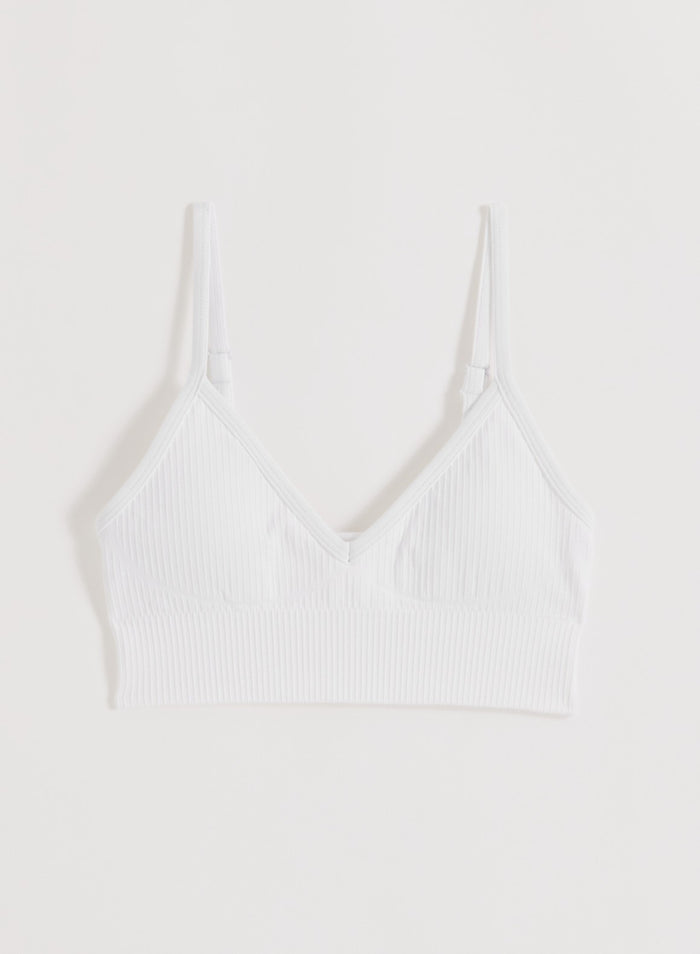 White ribbed seamless sports bra by aim'n featuring a deep cut neckline and thin adjustable straps.