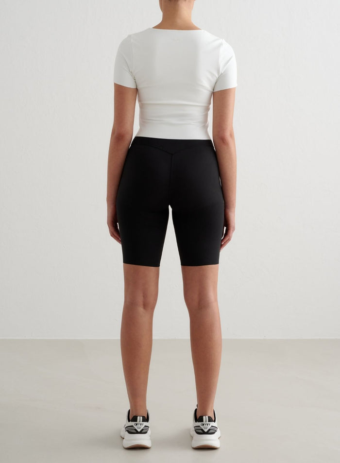 White Sense Short Sleeve Bralette with a second skin feel, shown from the back with black biker shorts.