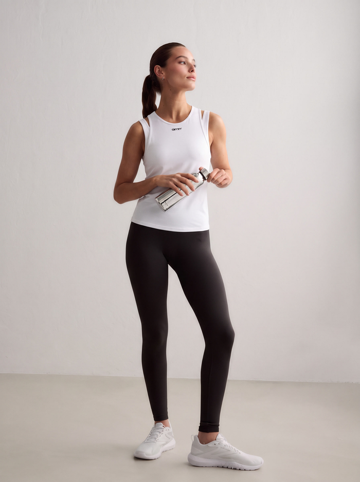 A model wearing a white Soft Basic Singlet holding a water bottle [S - 174 cm]