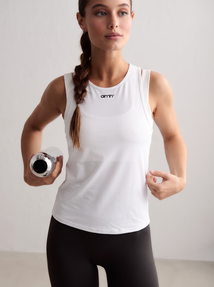 Model wearing a white Soft Basic Singlet and holding a water bottle [S - 174 cm]